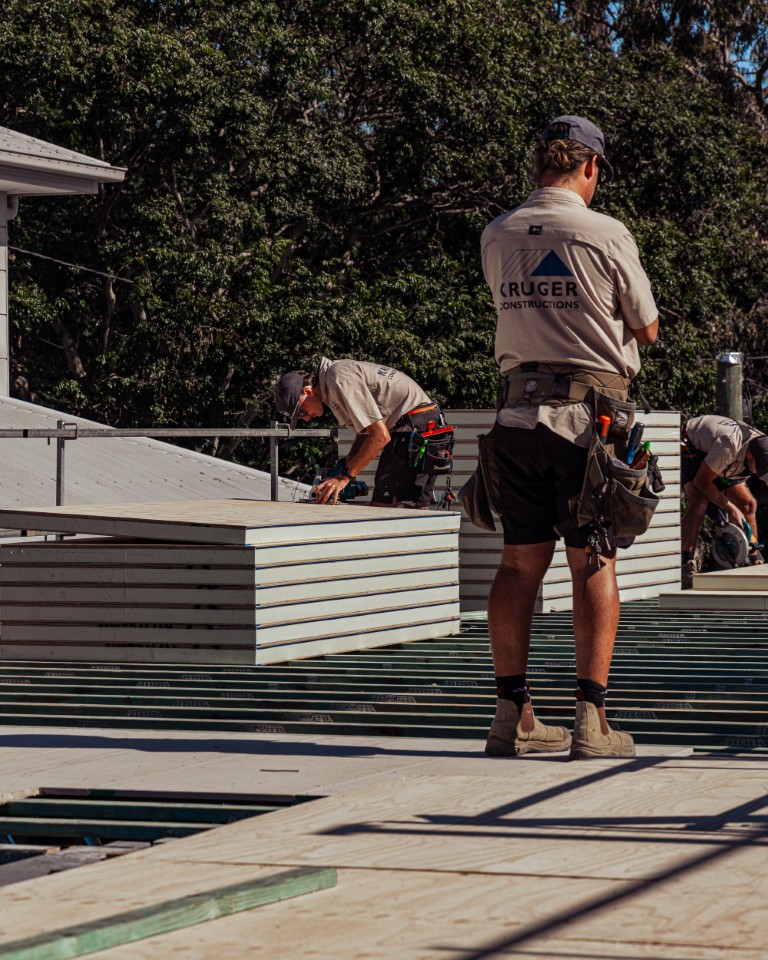 Installer standing on the upper-floor steel joists while another lays Platinum "R" Floor alongside