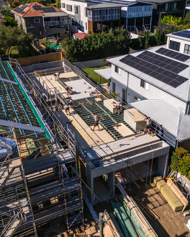 Aerial of installers laying Platinum "R" Floor across upper-floor steel joists between neighbouring Brisbane homes
